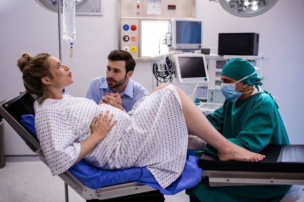 Clinica Villa Margherita Medico che esamina una donna incinta durante il parto mentre tiene la mano dell'uomo