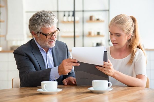 Studio Legale Nardone Piccoli & Associati Consulente legale maturo che legge il documento e spiega i dettagli al giovane cliente