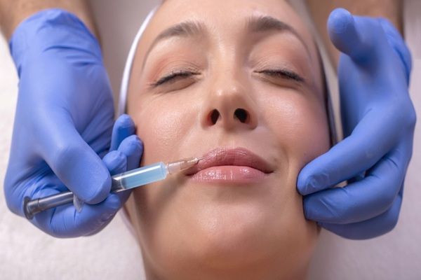 Centro Medico Parioli Dottore in guanti di gomma che fa chirurgia plastica facciale su una giovane donna felice