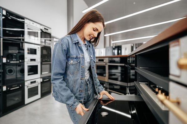 Euronics Nova Giovane donna castana che sceglie nuova stufa elettrica in un ipermercato