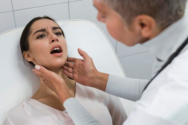 Medico che controlla la tiroide di un paziente I 10 migliori chirurghi tiroidei a Roma