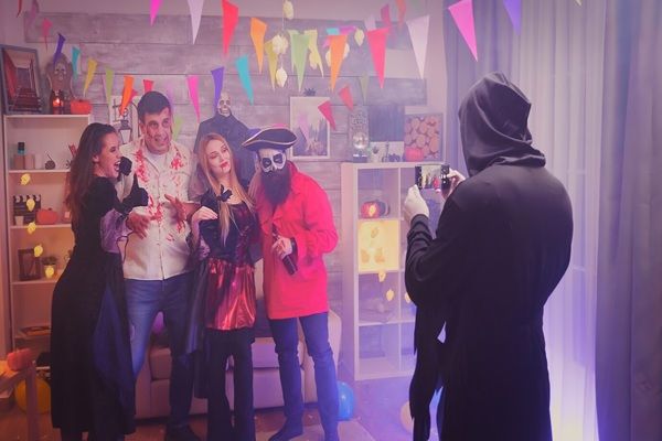 Fugacemente - Escape Room Cinecittà Personaggi inquietanti che scattano una foto di gruppo alla festa di Halloween in una stanza decorata.
