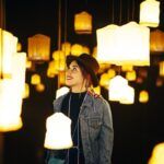 Primo piano di una giovane donna felice in una stanza con molti lampadari luminosi. I 10 migliori negozi di illuminazione a Roma