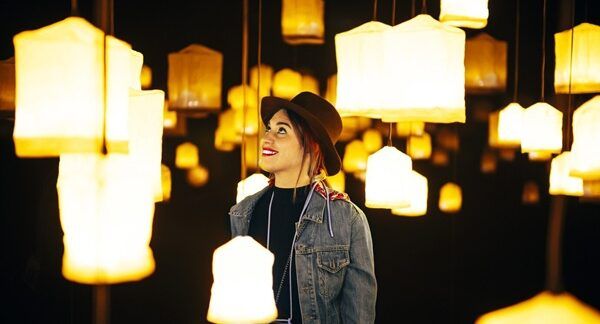 Primo piano di una giovane donna felice in una stanza con molti lampadari luminosi. I 10 migliori negozi di illuminazione a Roma