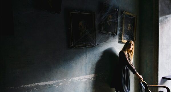 Le 10 migliori Escape Room a Roma Una ragazza cerca una sedia e si appoggia al muro con dei quadri in un bar