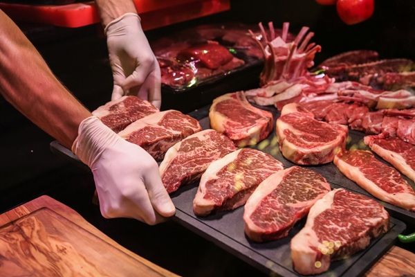 Macelleria Da Marco Vista laterale, lo chef prepara carne cruda marmorizzata per bistecche su un supporto
